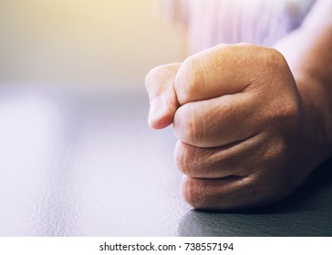 close up of a man fists clenched on office desk  in anger with window light effected, Vintage color tone. copy space