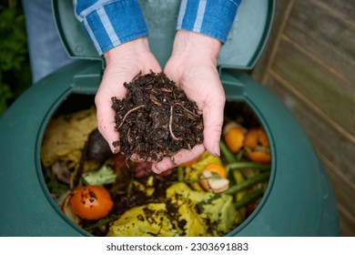 Close up of man in garden at home holding sustainable compost made from rotted down household food waste with worms visible - Shutterstock ID 2303691883