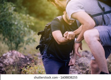Close up of man getting help to climb a rock, Helping hands, Overcoming obstacle concept