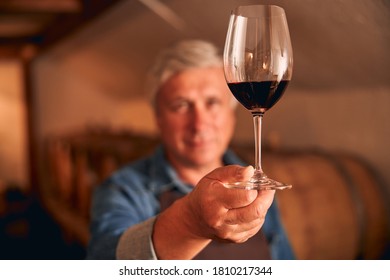 Close up of man with glass of alcoholic drink in his hand standing in wine cellar - Powered by Shutterstock