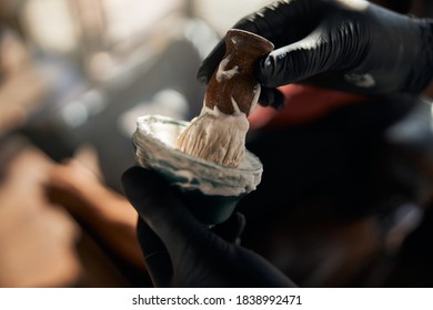 Close up of man hairdresser in sterile gloves putting shave brush into bowl with shaving cream - Powered by Shutterstock