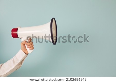 Close up of man hand hold loudspeaker advertise good sale deal or discount. Picture isolated on green studio background. Male with megaphone make announcement of promotion. Copy space.