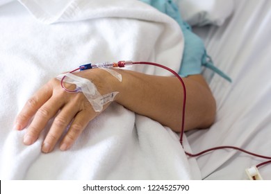 Close up Man hand hold a patients hand who have a blood transfusion in the hospital with copy space background.