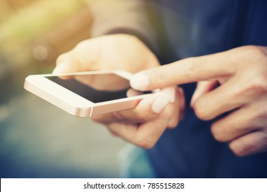 Close up man hand hold using smart phone on outdoor park street background. Copy space of technology business and travel holiday concept. Vintage tone filter effect color style.