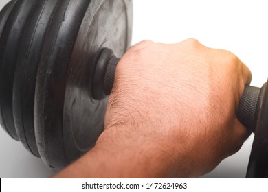 Close Up A Man Hand Is Holding Black Dumb Bell Over White Background. Dumb Bell Is An Equipment Of Build Up Muscle.