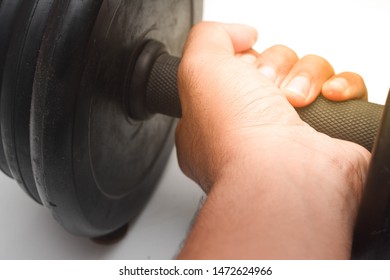 Close Up A Man Hand Is Holding Black Dumb Bell Over White Background. Dumb Bell Is An Equipment Of Build Up Muscle.