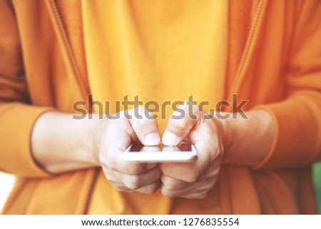 Close up of a man hand holding using mobile smart phone outdoor cellphone in public park. with filter Tones vintage effect ,Warm tones.