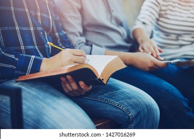 Close Up Of  A Man Hand Holding  And Writing On Bible While Fellowship With Christian Group  In Sunday School Class Room