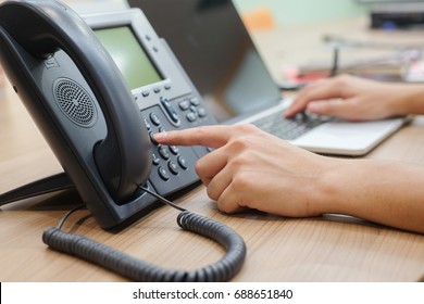 close up man hand pointing try to press button number on telephone office desk.multitasking employee concept