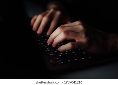 Close up man hand typing keyboard on laptop in darkness operating room, cyber security concept. Hacker using laptop