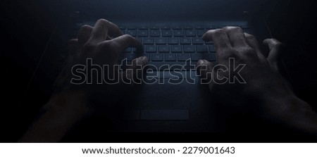 Close up man hand typing keyboard on laptop in darkness operating room, cyber security concept. Hacker using laptop