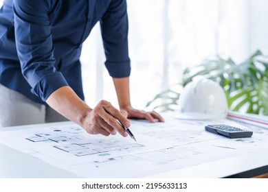 Close up man hand working of Architect blueprint at desk in construction work. - Shutterstock ID 2195633113