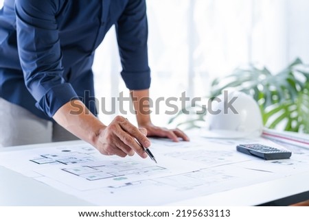Close up man hand working of Architect blueprint at desk in construction work.