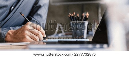 Close up man hand working of Architect sketching pencil project on blueprint at site construction work. Concept of architect, engineer in the office desk construction project banner