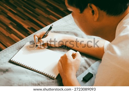 Close up of man hand writing notes in spiral notebook while sitting on bed, journaling and planning at home