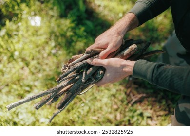 Close up of a man hands as he gathers dry sticks and branches in a peaceful forest setting. Perfect for themes of outdoor adventure, survival, and nature exploration. - Powered by Shutterstock