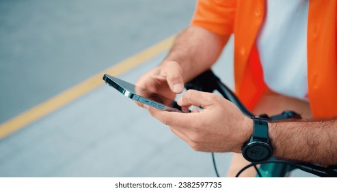 Close up man hands holdilg mobile phone. Unrecognizable male cyclist use smartphone typing a message and while standing near bike. - Powered by Shutterstock