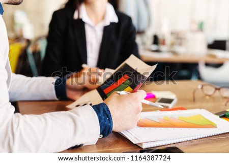 Close up of man hands holding documents while he is sitting in a business meeting .Table full of histogram and gadgets.