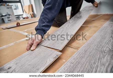 Close up of man hands laying laminate wooden planks on the floor in apartment under renovation. Male construction worker installing timber laminate flooring at home. Hardwood floor renovation concept. ストックフォト © 