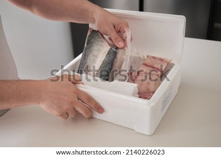 Close up of a man hands opening his weekly delivery of fish in an EPS isothermal box.