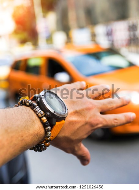 Close up of man\
hands with outdoor watch and stone bracelet. Man raising him hand\
for calling taxi in\
Istanbul.