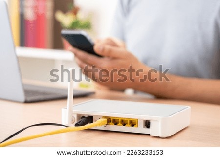 Close up of man hands using multiple devices with broadband router on foreground