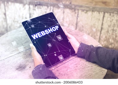 Close up of man hands using tablet with creative webshop inscription on screen. Wooden outdoor table in the background. Online shopping, e-commerce, internet purchases concept