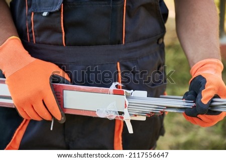 Close up of man hands in work gloves holding welding electrodes. Male builder with coated metal wires or welding rods sticks in his hands.