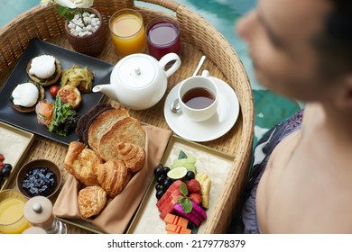 Close Up Of A Man Having Floating Breakfast Tray In Luxury Pool Hotel. Young Male Enjoying Morning Coffee In Tropical Resort. Relaxing, Exotic Summer Travel, Holiday, Vacation And Weekend