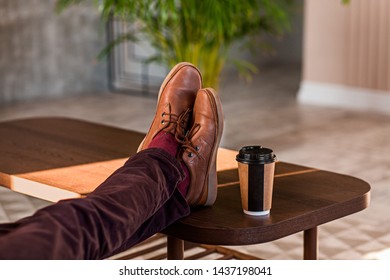 Close Up Of A Man Holding His Legs On A Table, Relaxing And Drinking Coffee In An Office