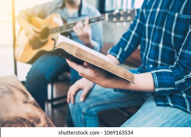 close up of a man holding hymn books and sing a song while his friend playing guitar, praise and worship concept