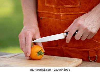 Close up of man holding sharp knife, slicing juicy red tomato. Preparing vegetables for an outdoor barbecue. - Powered by Shutterstock