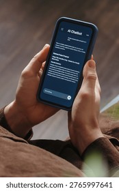 Close up of a man holding a smartphone, using an AI chatbot app for work, brainstorm a business project. Personal Artificial intelligence assistant helping with productivity. Vertical photo