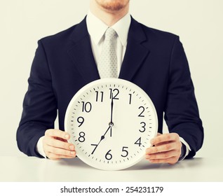 close up of man holding wall clock