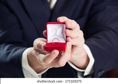 Close Up Of Man Holding Wedding Ring And Gift Box.