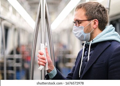 Close up of man holds a handrail in public transportsubway through a napkin, to protect yourself from contact with viruses, germs during a coronavirus pandemic, covid-19. Quarantine concept - Shutterstock ID 1676572978