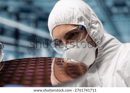 Close up of man inspecting microelectronic silicon wafer components in smart factory. Worker verifying semiconductor substrate integrated circuits quality in futuristic foundry