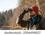 Close up of a man looking through binoculars, outdoors.