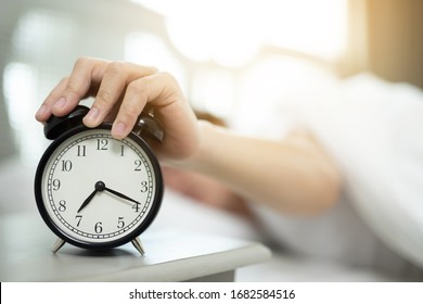 Close Up Of Man Lying In Bed Turning Off Hand Reaching Out For Alarm Clock Color Black Wake Up Late At Morning At 7.20 Am.