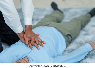Close up man lying down while another individual, likely a medical professional, is performing a CPR chest compression, potentially in response to heart attack.