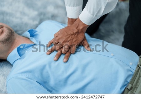 Close up man lying down while another individual, likely a medical professional, is performing a CPR chest compression, potentially in response to heart attack.
