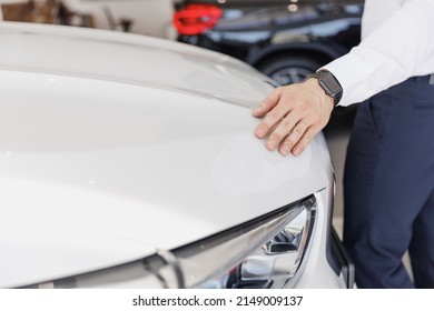 Close up man male arm customer buyer client wearing white shirt chooses auto wants to buy new automobile touch glossy hood in showroom vehicle salon dealership store motor show indoor Sales concept