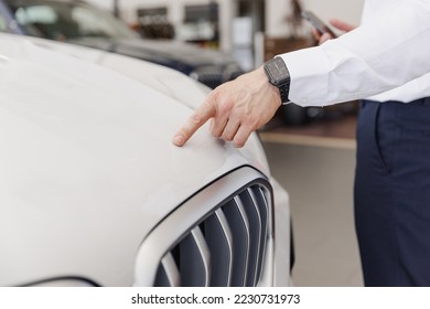Close up man male hand customer buyer client in white shirt chooses auto wants to buy new automobile touch hood of BMW brand in showroom vehicle salon dealership store motor show indoor Sales concept