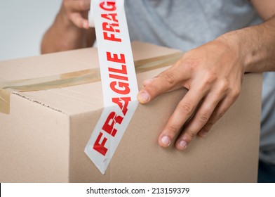 Close up Of A Man Packing Cardboard Box With Sellotape