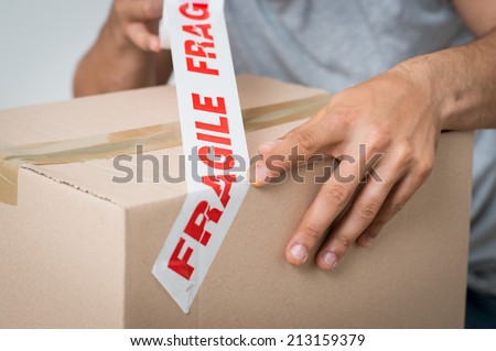Close up Of A Man Packing Cardboard Box With Sellotape