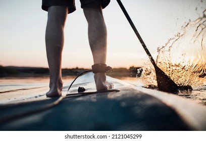 Close Up Of Man Paddleboarding At Sunset