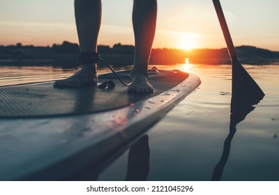 Close Up Of Man Paddleboarding At Sunset Lake