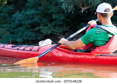 Close Up Of Man Paddles Kayak On The Danube River Near Green Trees