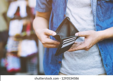 close up man person holding an empty wallet in the hands of an man no money out of pocket in front of the shop store. No money to pay shopping purchase Sell or Payment. 