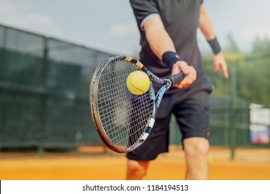Close up of man playing tennis and beating the ball with a racket. - Powered by Shutterstock